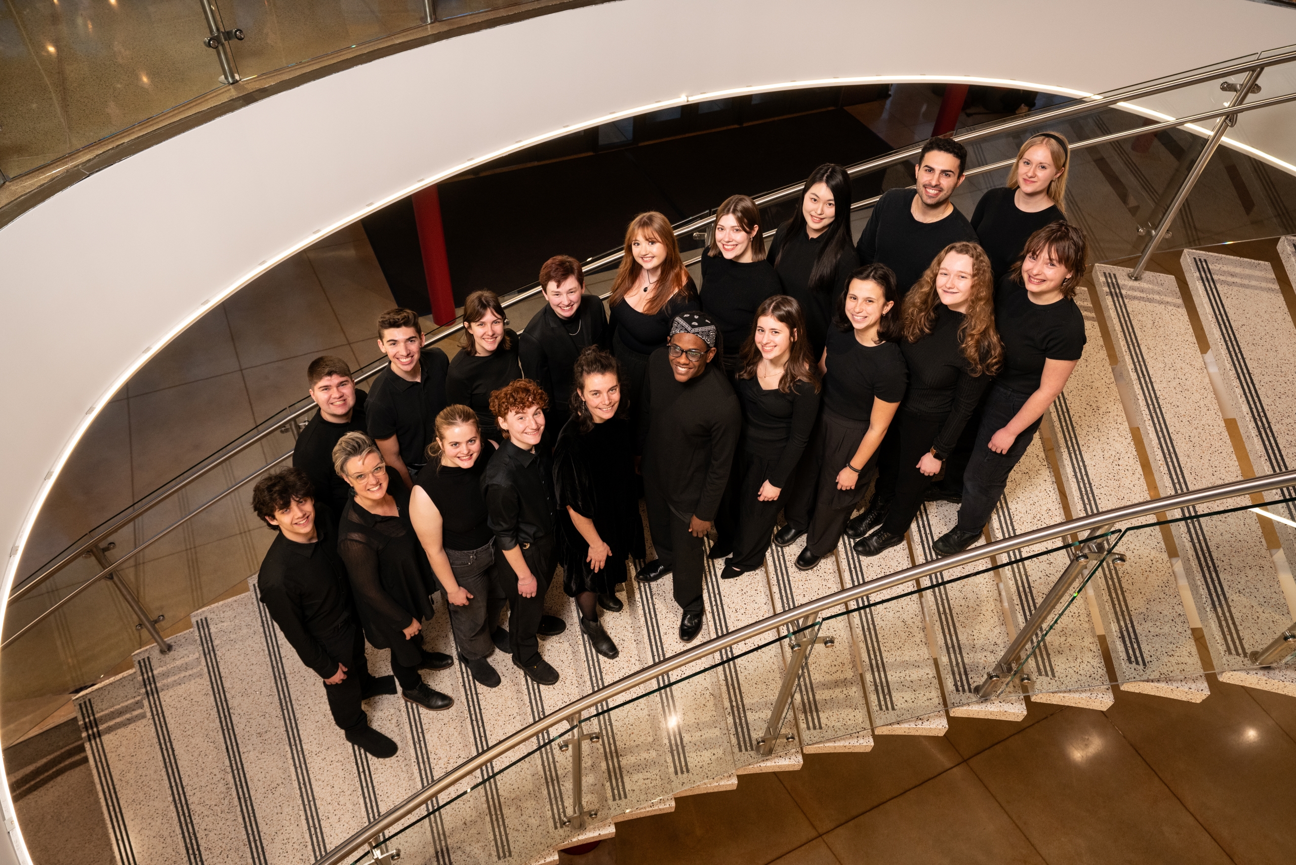 Group of people wearing black pose on a staircase